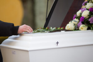 closeup-shot-of-a-person-hand-on-a-casket-with-a-blurred-background-eosfiera