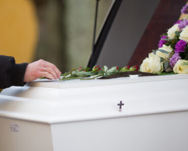 closeup-shot-of-a-person-hand-on-a-casket-with-a-blurred-background-eosfiera